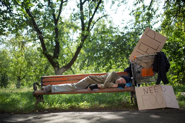 Homeless old man on the bench in city park. — Stock Photo, Image