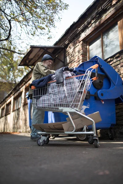 Dakloze man op zoek naar voedsel in de prullenbak kan. — Stockfoto