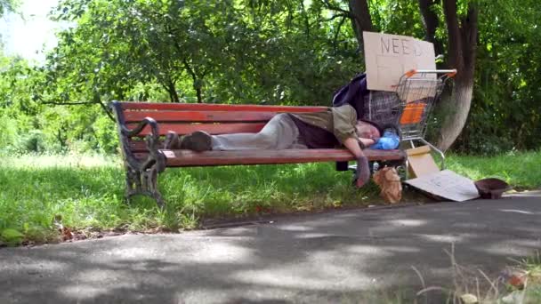 Filmati con vecchio vagabondo ubriaco, che dorme sulla panchina in strada . — Video Stock