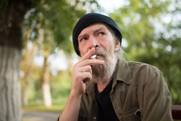 Portrait of homeless old man smoking.