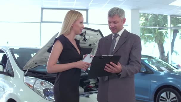 Sala de exposición automática, mujer joven eligiendo el coche hablando con el distribuidor . — Vídeo de stock