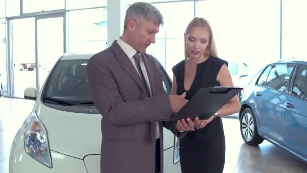 Bil showroom, bilhandlare pratar med kunden kvinna. — Stockvideo