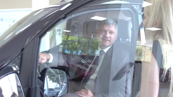 View of a dealer showing new car to customer, — Stock Video