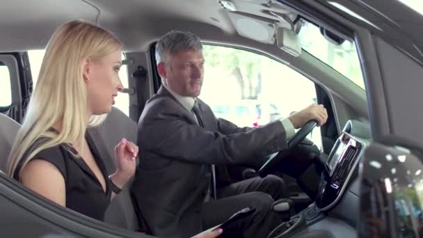 Zobacz młodą kobietę siedzącą na przednim siedzeniu samochodu electro, zadawanie pytań do dealera. — Wideo stockowe