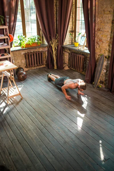 Вид спортивного мужчины, делающего отжимания на полу дома . — стоковое фото