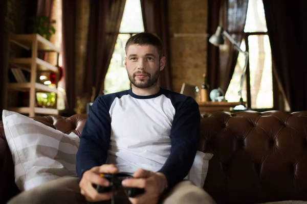 Ansicht eines jungen Mannes, der auf der Couch sitzt und den Steuerknüppel hält. — Stockfoto