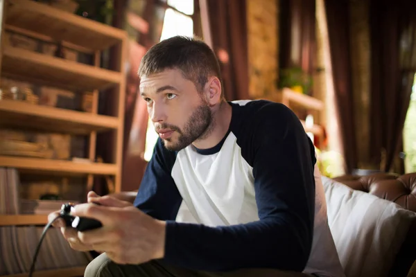 Seitenansicht eines gutaussehenden jungen Mannes mit Spielcontroller, der Videospiele spielt. — Stockfoto