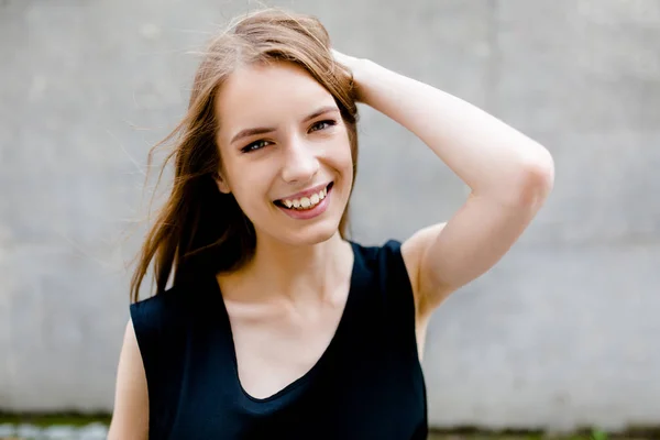 Vista de cerca de la joven sonriente dama de pie contra la pared gris . — Foto de Stock