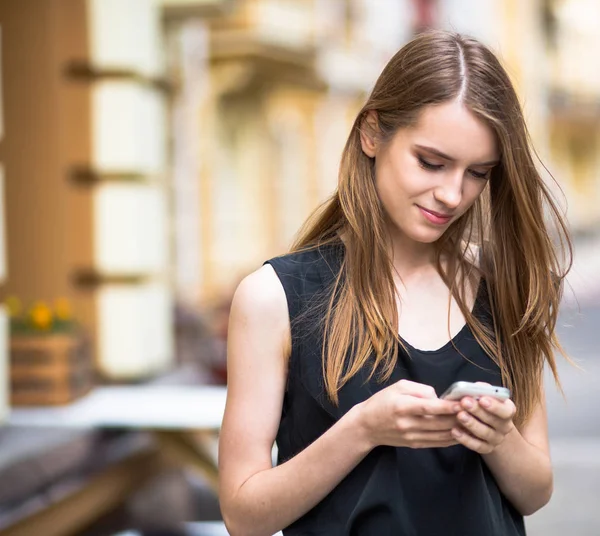 Вид симпатичной молодой женщины, посылающей смс по телефону на улице . — стоковое фото