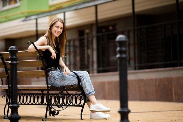 Schönes Mädchen sitzt auf der Bank. — Stockfoto