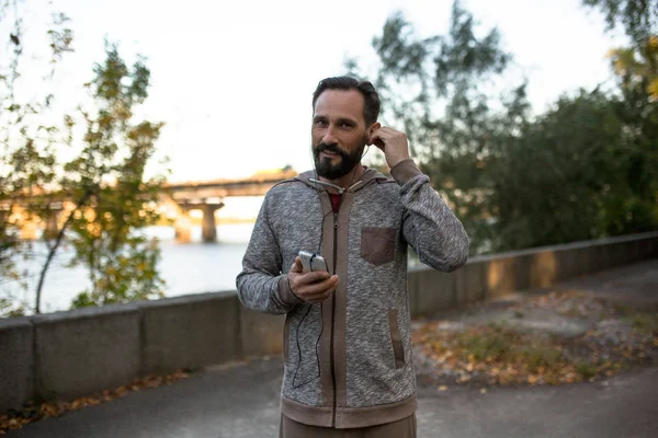 Hombre corriendo y ajustando auriculares . — Foto de Stock