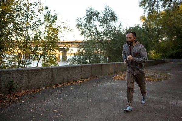 Vista del hombre corriendo por la orilla del río en la ciudad . — Foto de Stock