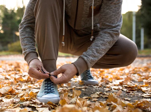 Man vetersluiting zijn sportieve schoenen klaar om te joggen in atumn park. — Stockfoto