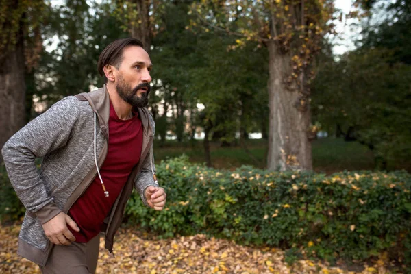 Vista lateral do homem correndo na floresta de outono . — Fotografia de Stock