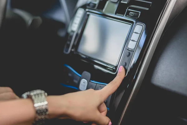 Frau untersucht Bedienfeld in Neuwagen. Wahl eines neuen Fahrzeugs, Nahaufnahme der Fingertasten in einem Auto. — Stockbild Frau untersucht Schalttafel in Neuwagen. — Stockfoto
