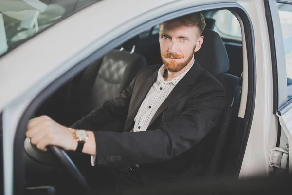 Молодий красивий чоловік їде машиною, оглядаючи інтер'єр автомобіля . — стокове фото