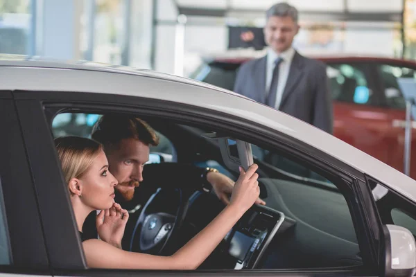 Couple in auto showroom choosing a new vehicle. — Stock Photo, Image
