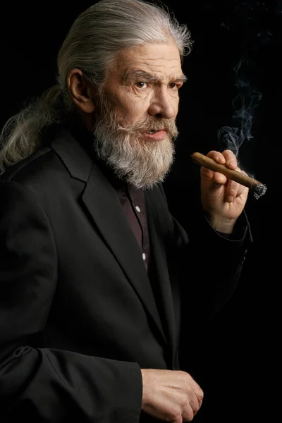 Old man with long grey hair holding cigar. — Stock Photo, Image