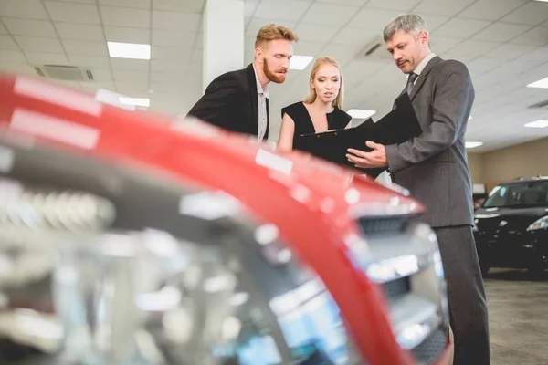 Vehicle dealer selling electro car to young couple. — Stock Photo, Image