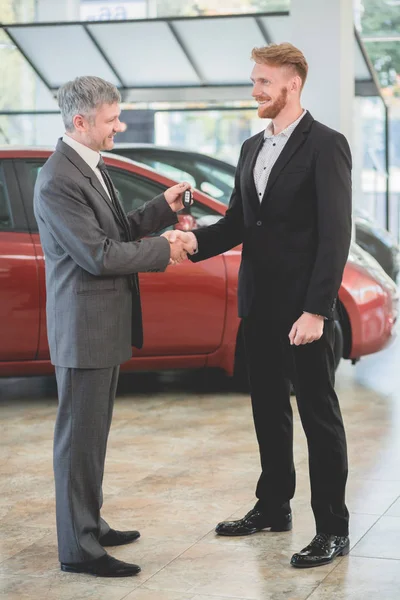 Vehicle dealer passing key from new car to a buyer. — Stock Photo, Image