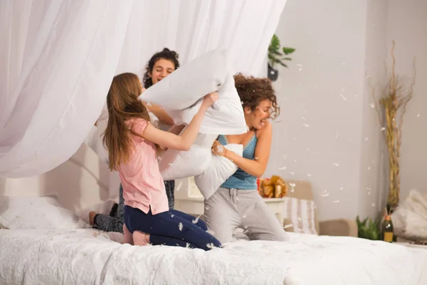 Chicas en la cama teniendo pelea de almohadas en pijama —  Fotos de Stock