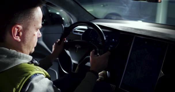 Człowiek siedzi w kierownicy samochodu Tesla — Wideo stockowe