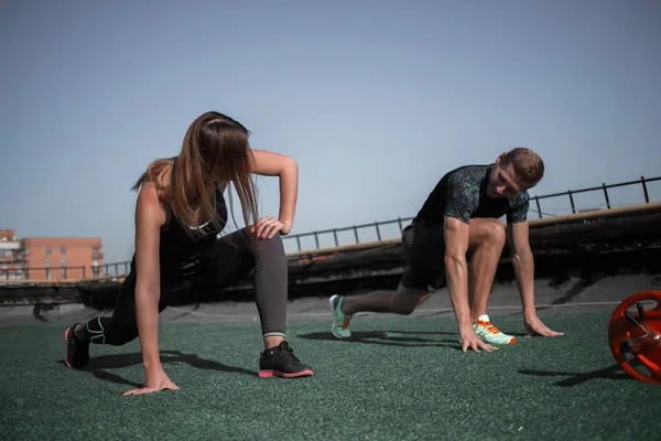 Man en vrouw het beoefenen van sport op het dak. — Stockfoto