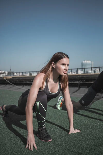 Sportieve jonge vrouw doen streching oefeningen op het dak. — Stockfoto