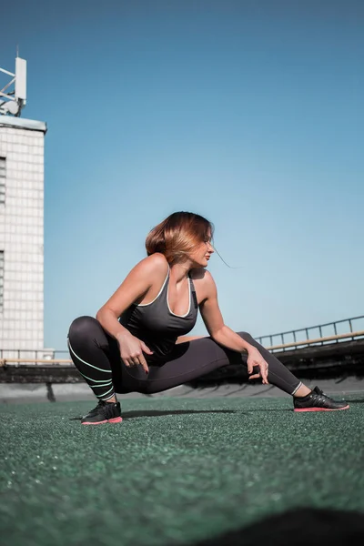 Jonge sportieve vrouw doen diepe lunges op het dak. — Stockfoto