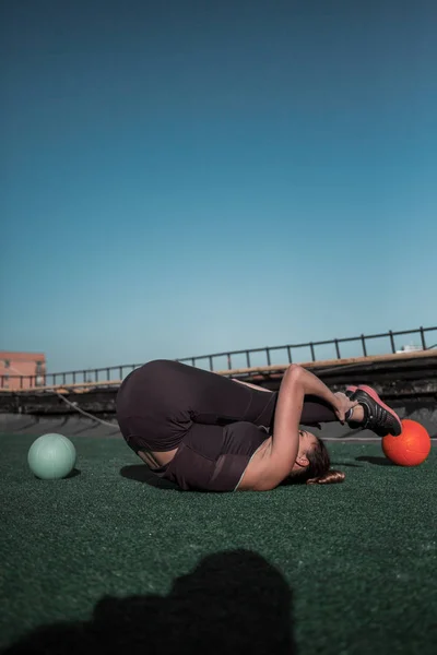 Sportos nő fejlesztése a stretching képességét a tetőn. — Stock Fotó