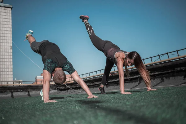 Sportovně založení lidé dělají sportovní cvičení na střeše budovy. — Stock fotografie