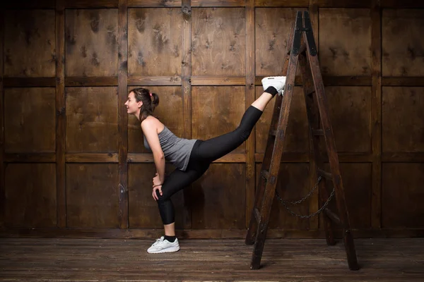 Strong woman using a wooden ladder — Stock Photo, Image