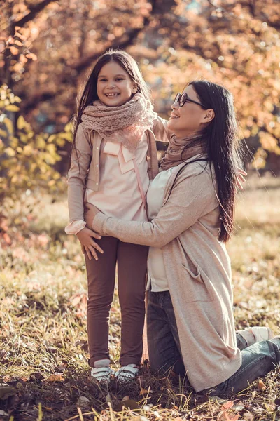 Hermosa joven y su hijo en el jardín de otoño — Foto de Stock