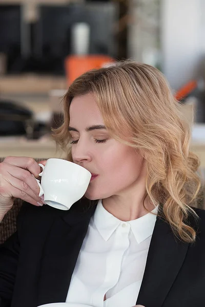 Красивая деловая женщина пьет кофе в офисе — стоковое фото