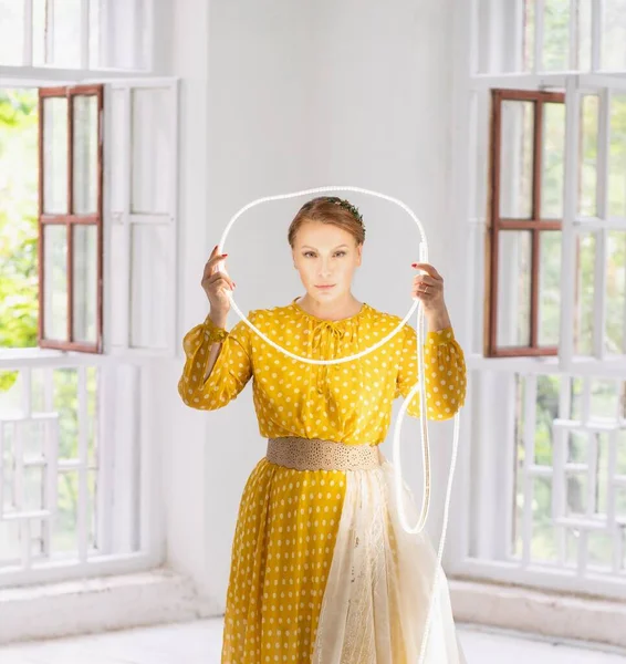 Mittelschuss. Model in einem gelben Kleid posiert mit einem Kreis aus LED-Streifen — Stockfoto