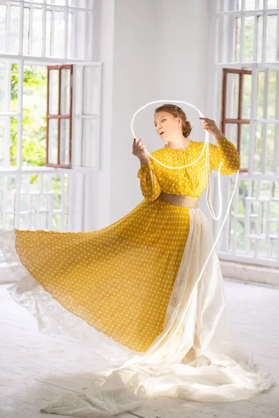 Dançarina em um vestido amarelo faz Pa segurando um círculo brilhante em suas mãos . — Fotografia de Stock