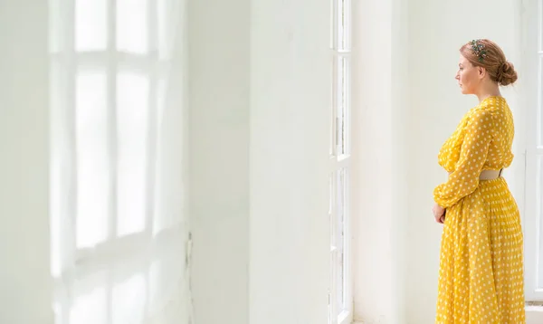 Mujer solitaria y hermosa de mediana edad de pie junto a la ventana y esperando a un hombre —  Fotos de Stock