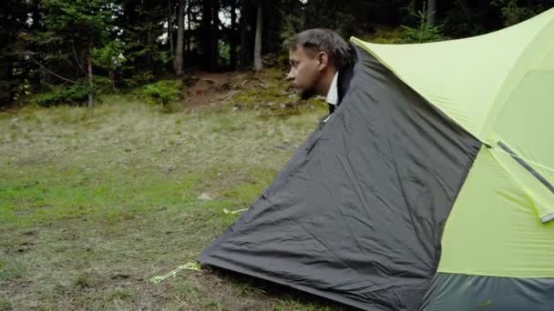 Um homem em um acampamento olha em volta na floresta — Vídeo de Stock