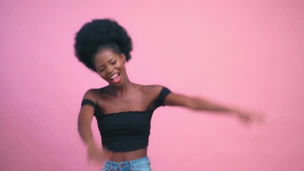 Szexi csinos afro-amerikai modell mosolygós és pózol rózsaszín háttér — Stock videók