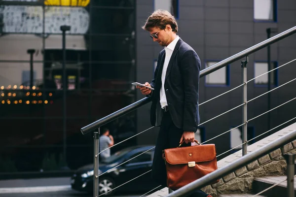 멋진 양복을 입고 휴대폰을 들고 있는 은행가가 계단을 내려가고 있습니다 — 스톡 사진