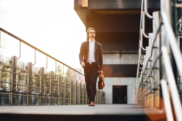 Empresario exitoso con un maletín en la mano camina por la calle en verano durante la puesta del sol — Foto de Stock