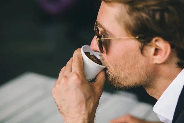 Atractivo barbudo joven es beber café primer plano disparo —  Fotos de Stock