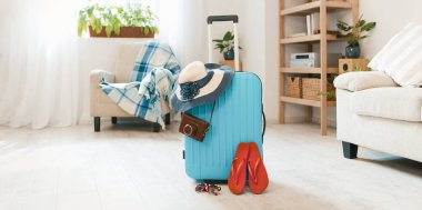 Blue suitcase with havaianas and hat at home interior. clipart