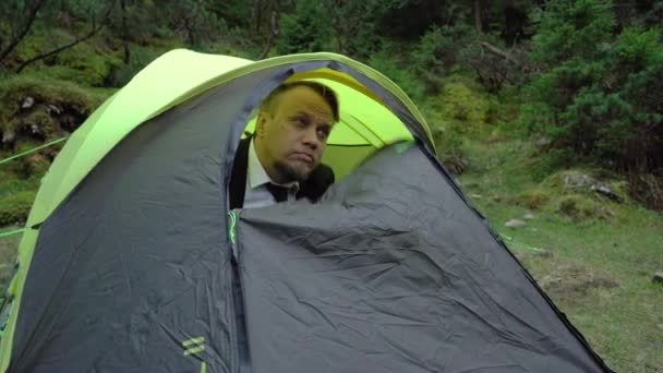 Uomo d'affari turista sbirciando fuori da una tenda per trascorrere del tempo in natura — Video Stock