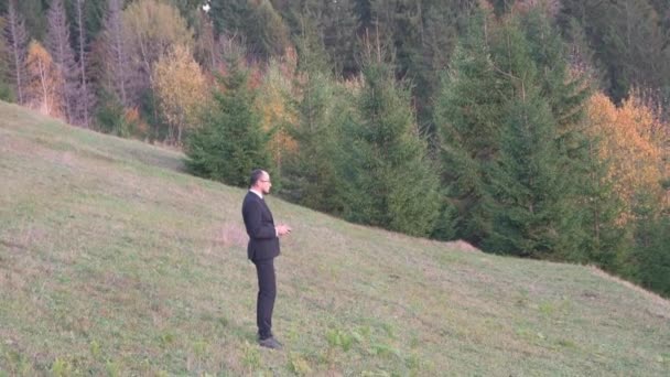 Trabalhador de escritório lança um Quadcopter em uma colina no verão na frente da floresta — Vídeo de Stock