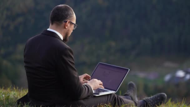 Gestionnaire se détend avec un ordinateur portable dans une belle nature — Video