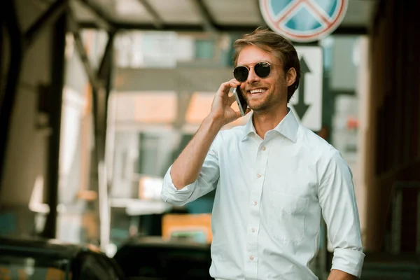 선글라스를 끼고 있는 사업가가 전화로 웃으며 말하고 있습니다 — 스톡 사진