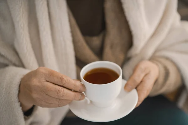 Kvinnliga händer som håller en vit kopp med hett te — Stockfoto