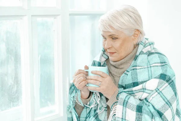 Mujer mayor pensativa con una taza de té en la mano . — Foto de Stock