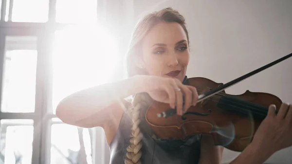 Молодая привлекательная женщина в красивом платье играет скрипку с вдохновением — стоковое фото